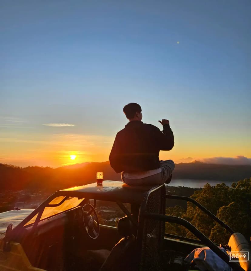Tourists watching sunrise from a jeep on Mount Batur